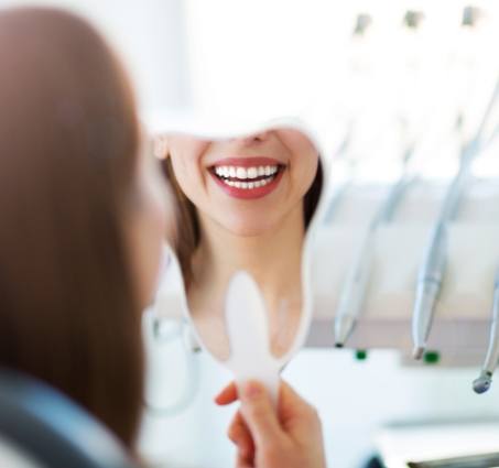 Woman looking at her smile after restorative dentistry