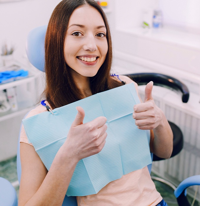 Woman in dental chair giving thumbs up