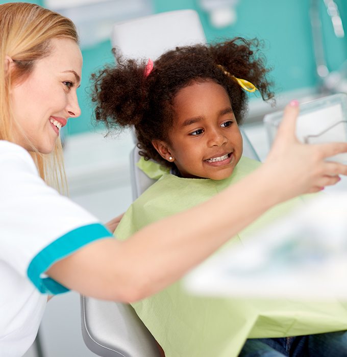 Child looking at teeth after dental sealant placement