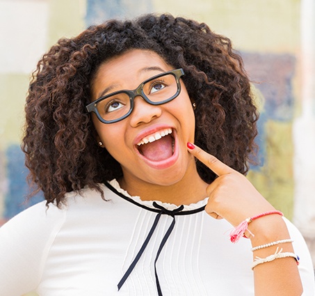 Woman pointing to her smile after cosmetic dentistry