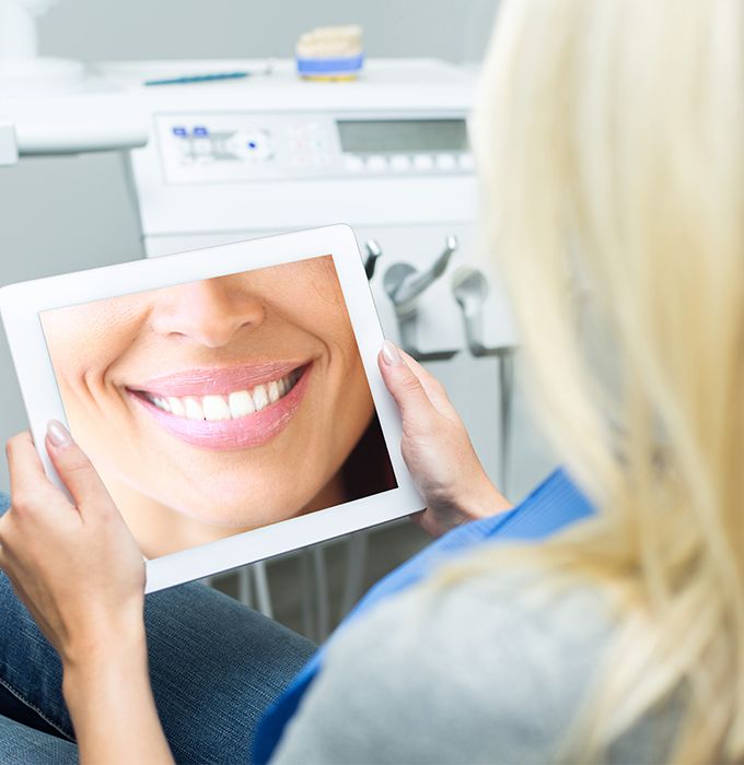 Woman looking at virtual smile design on tablet computer