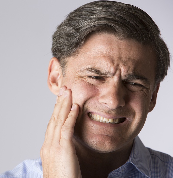 Man in need of emergency dentistry holding jaw in pain