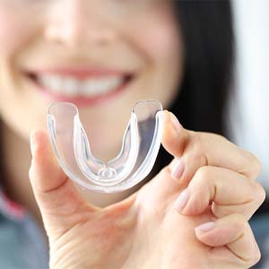 Woman with dental implants in Muskegon, MI holding mouthguard