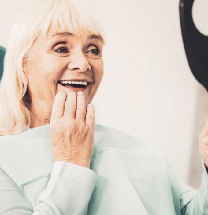 Woman admiring her new implant dentures in Muskegon 