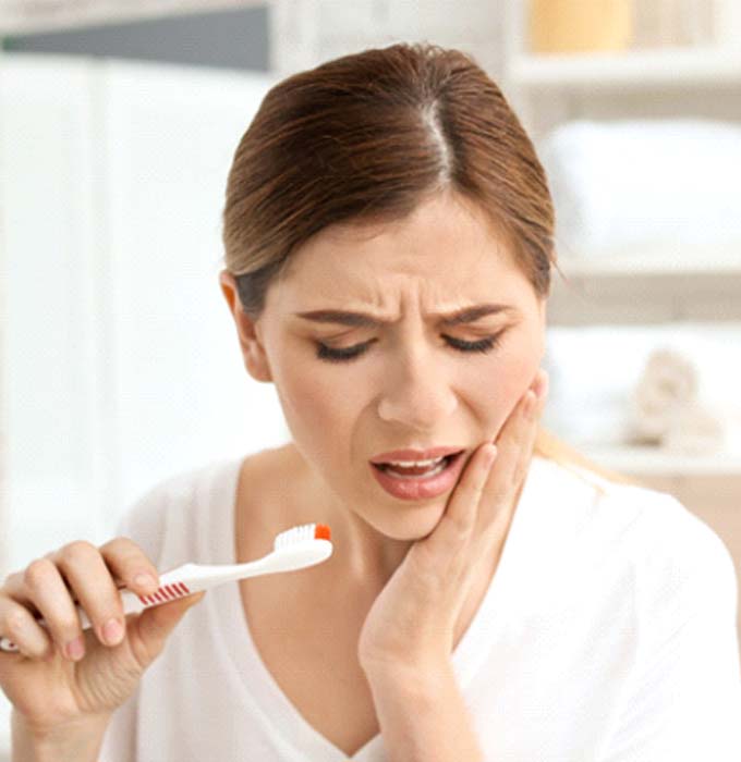 Woman with dental implants in Muskegon holding her face