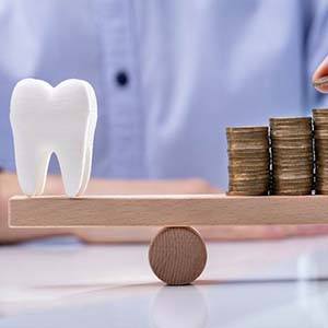 Man placing coins onto sawhorse with model tooth on it