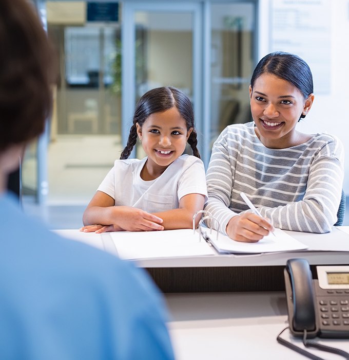 Mother and daughter filling out dental insurance forms at the dental office