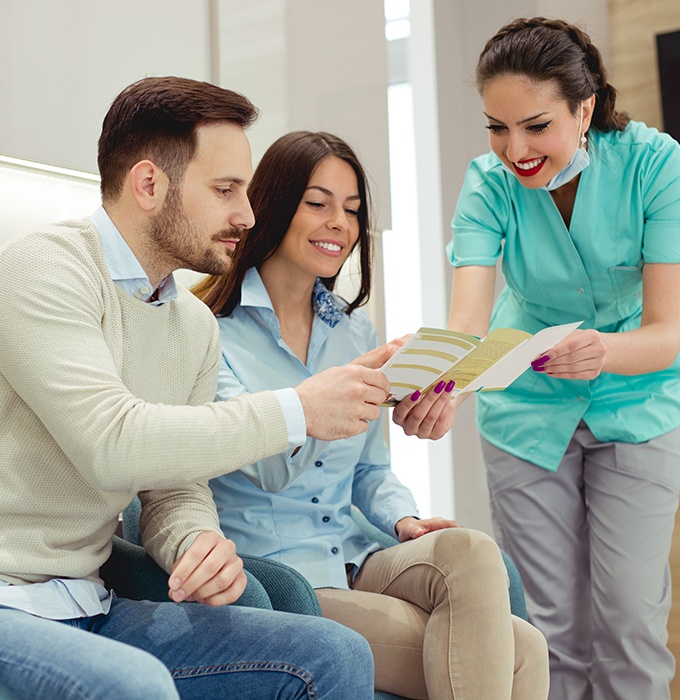 Dental team member giving patients dental insurance forms