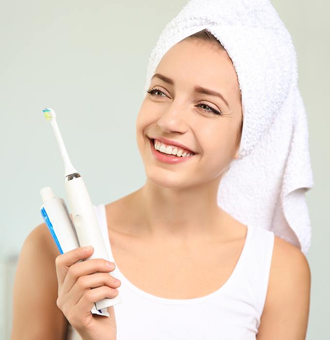 Woman holding up her at home dental hygiene products
