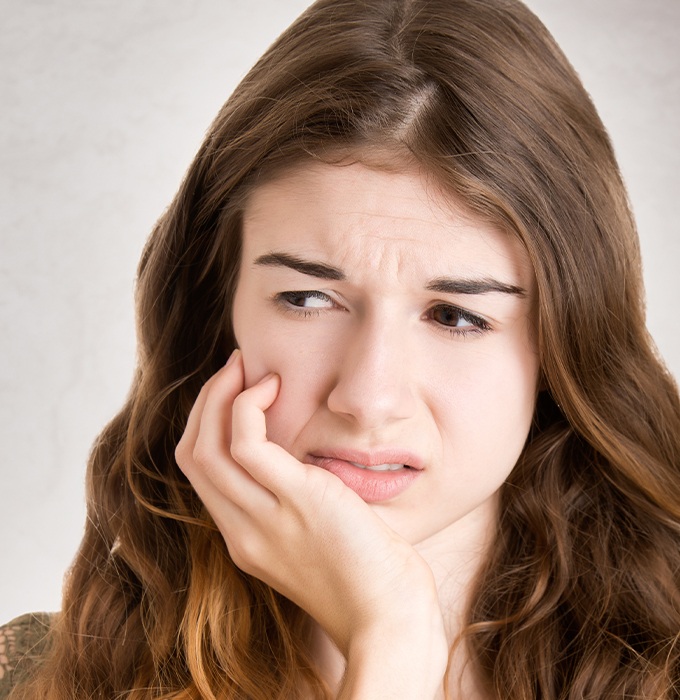 Woman in need of root canal therapy holding her jaw in pain