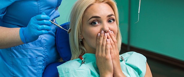 Woman covering smile before dental implant tooth replacement