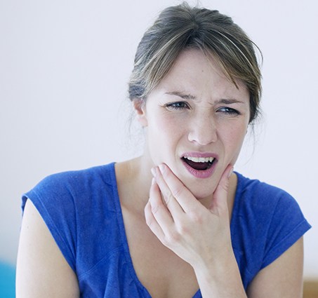 Woman in need of T M J therapy holding jaw in pain