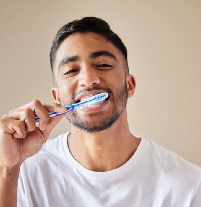 a man brushing his teeth to maintain their shine