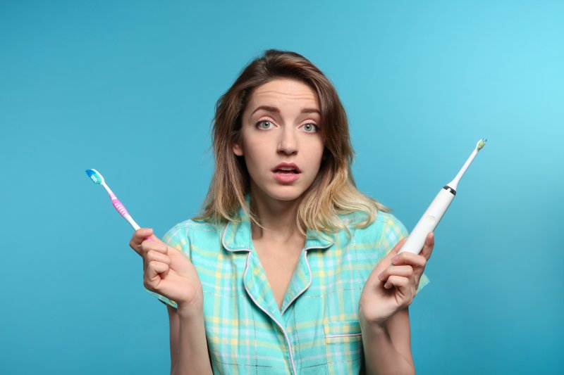 young woman choosing between electric and manual toothbrush