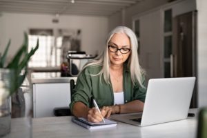 mature woman writing on notepad 